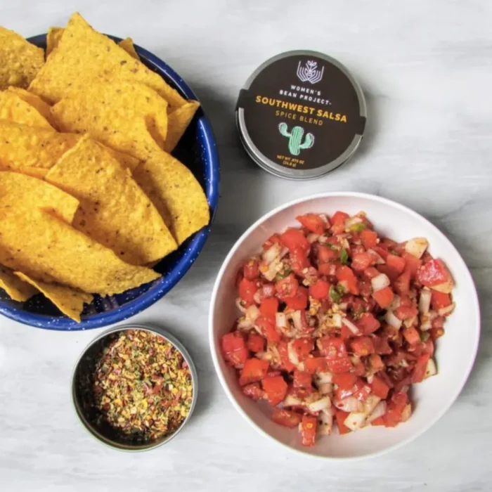 An open tin of Women's Bean Project Southwest Salsa SPice Blend next to chips and salsa.